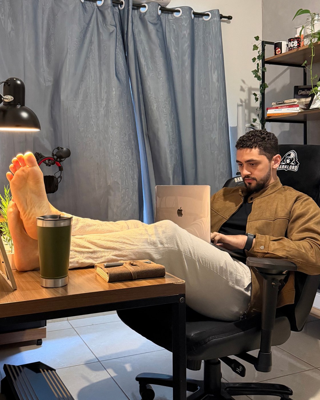 Luiz relaxado, pés na mesa, trabalhando com calma no notebook
